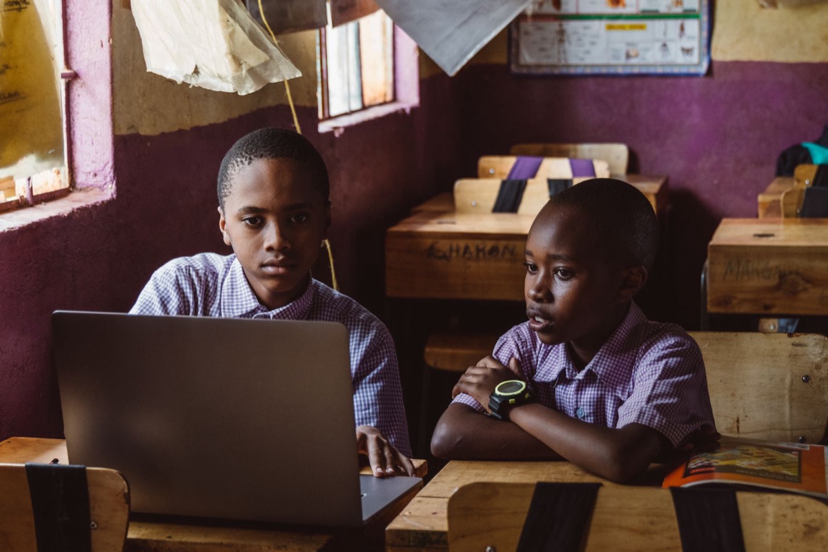 Two students at a classroom desk working on a laptop